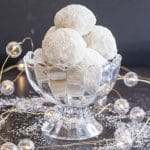 snowball cookies in a glass bowl with christmas lights on