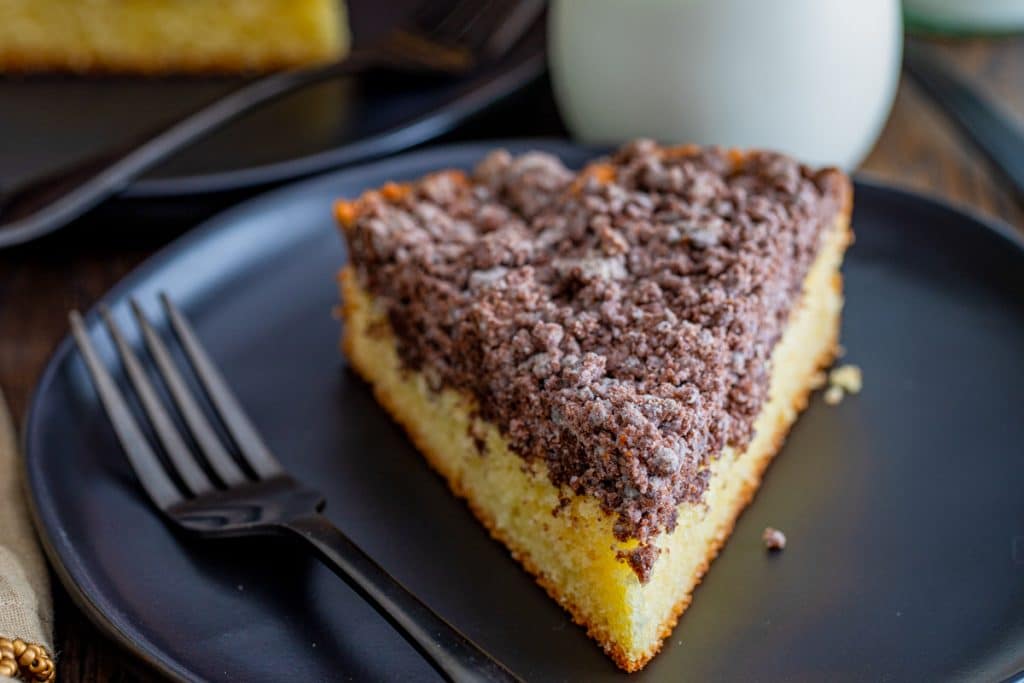 A slice of vanilla chocolate cake on a black plate.