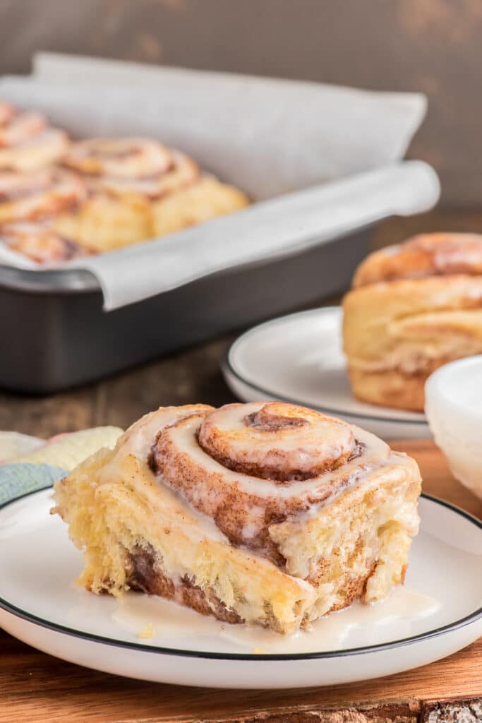 Cinnamon bun on a white plate and in the pan.