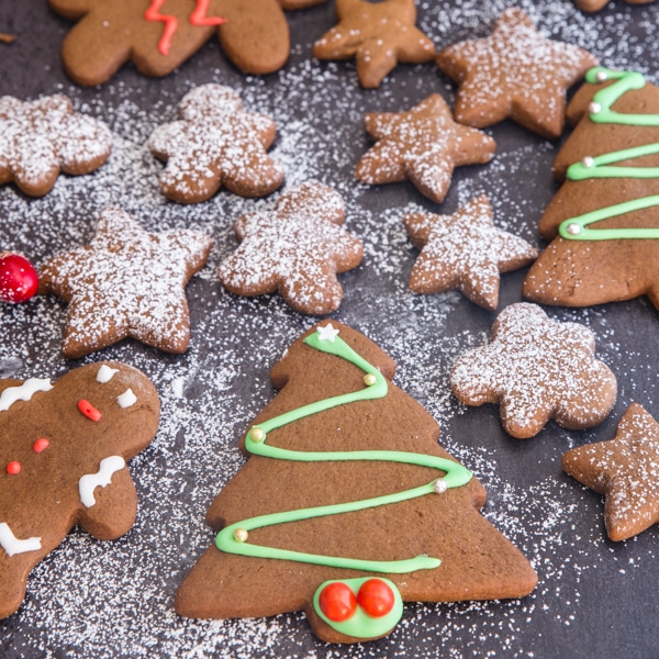 gingerbread cookies on a black board some decorated and some dusted with powdered sugar
