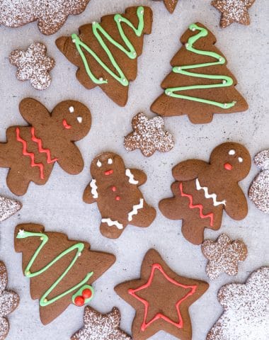 gingerbread cookies on a grey board, some decorated and some dusted with powdered sugar