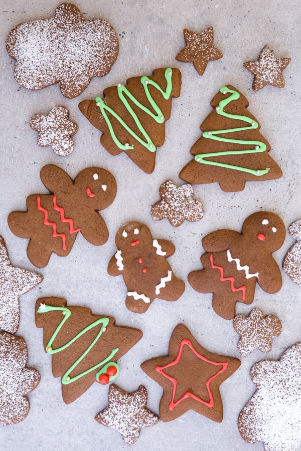 gingerbread cookies on a grey board, some decorated and some dusted with powdered sugar