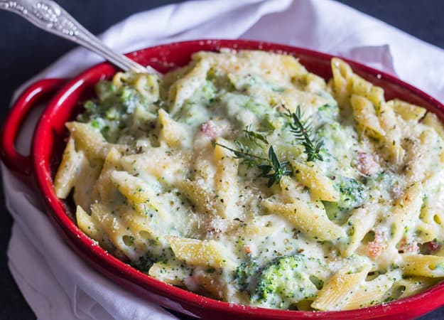 creamy broccoli bacon pasta casserole up close baked in a red dish