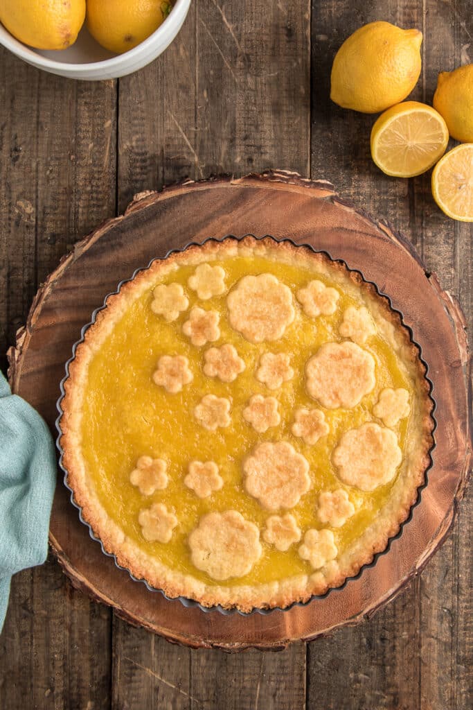 Crostata on a wooden plate with lemons.
