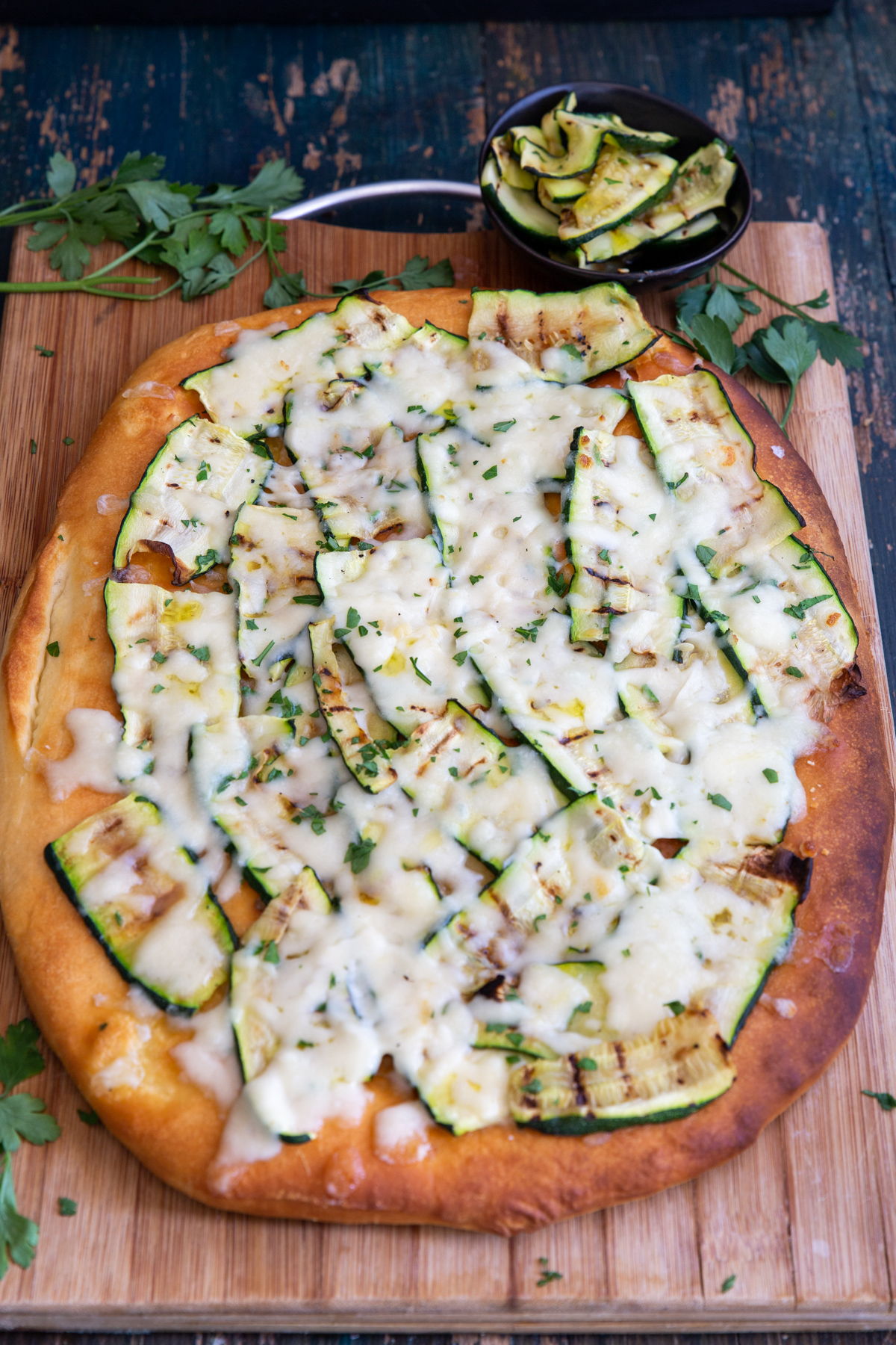 Grilled zucchini & cheese pizza on a wooden board.