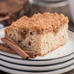 A slice of cinnamon crumb cake on a white plate.