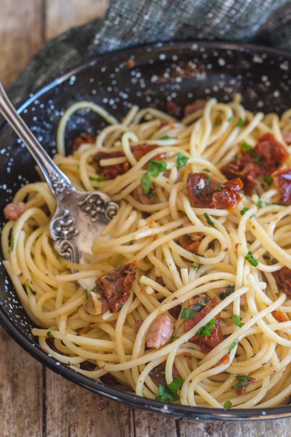 pasta in a black pan with sundried tomatoes and pancetta