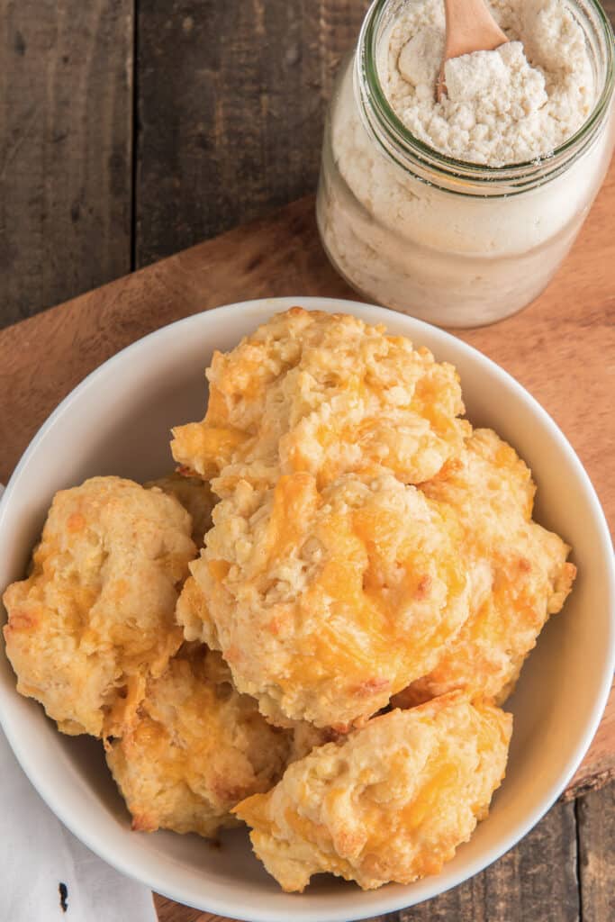 Biscuits in a white bowl with mix in a glass jar.