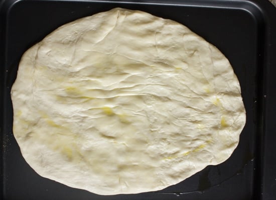 Pizza dough on a baking sheet.