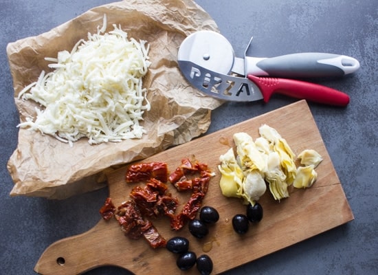 Ingredients for the pizza on a wooden board.