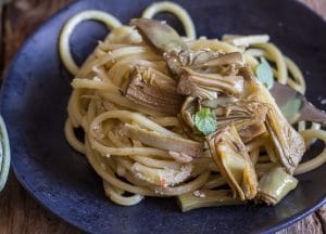 up close artichoke pasta on a black plate