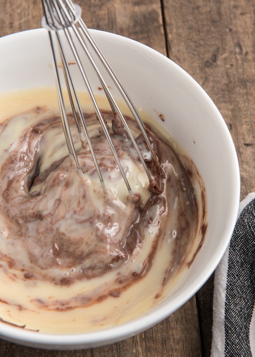 Combining the nutella and sweetened condensed milk in a white bowl.