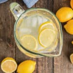 Citrus syrup drink in a jug with ice and lemon slices.