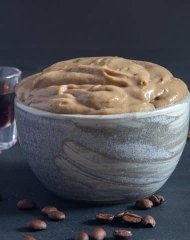 Coffee pastry cream in a grey bowl with a glass of coffee.