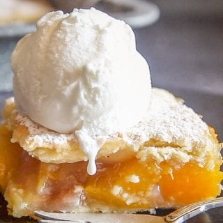 a slice of peach filled Italian crostata bars on a plate with a scoop of ice cream