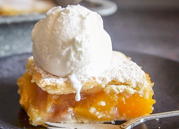 a slice of peach filled Italian crostata bars on a plate with a scoop of ice cream