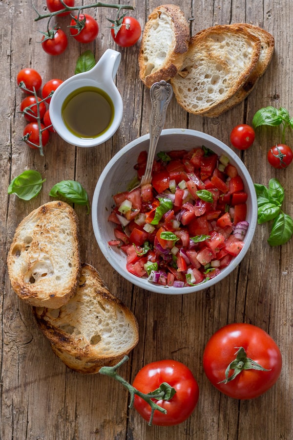 tomato bruschetta in a bowl and grilled bread on a board