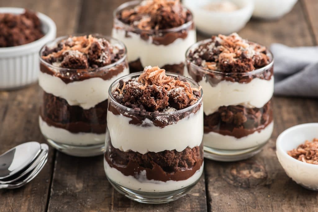 Brown parfaits in a glasses on a brown board.