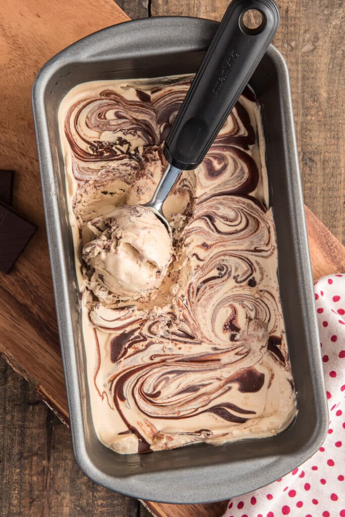 Coffee ice cream in a loaf pan with a scoop.