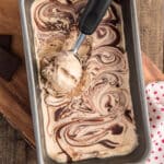 Ice cream in a loaf pan with a scoop on top.