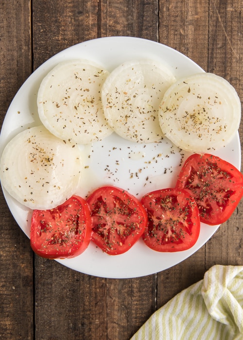 The sliced onions and tomatoes prepped on a white plate.