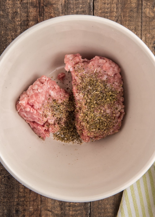 Mixing the ground pork and spices in a white bowl.