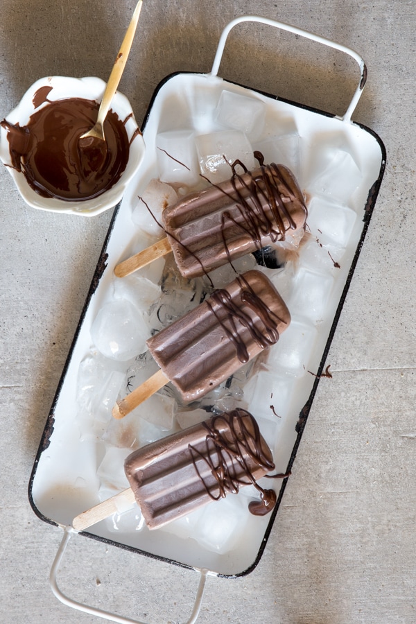 fudgesicles on a white tray drizzled with melted chocolate