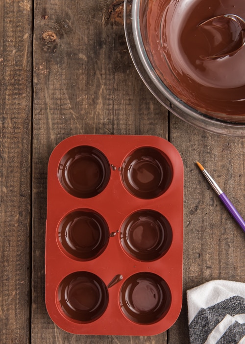 Lining the molds with melted chocolate.
