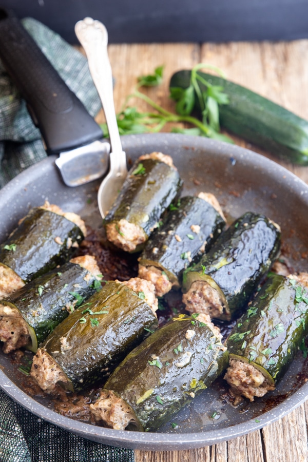 stuffed zucchini with a silver spoon in a black pan