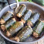 stuffed zucchini with a silver spoon in a black pan