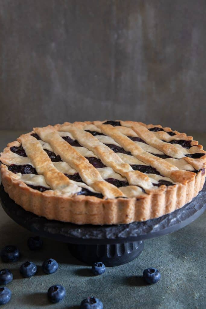 Blueberry crostata on a black stand.