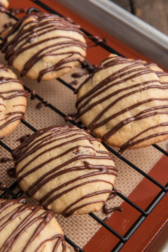 Brown sugar cookies drizzled with chocolate on a wire rack.