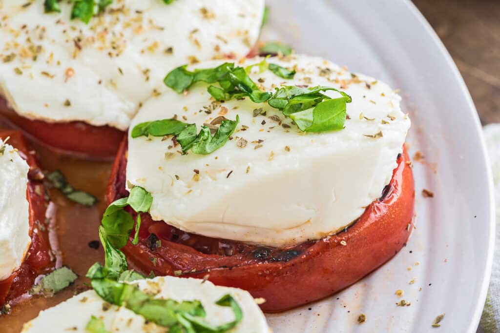 Grilled tomatoes on a white plate.
