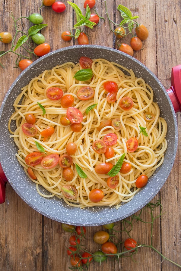 spaghetti aglio, olio e peperoncino in a pan with fresh chopped tomatoes