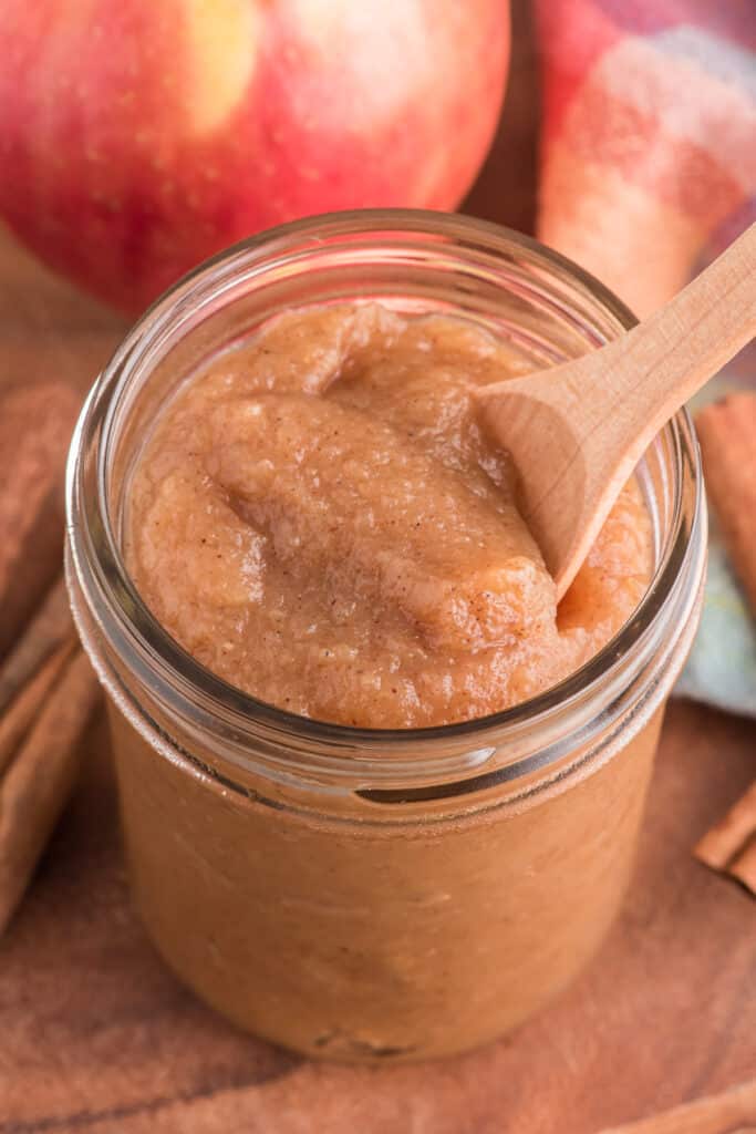 Apple butter with a spoon in a glass jar.