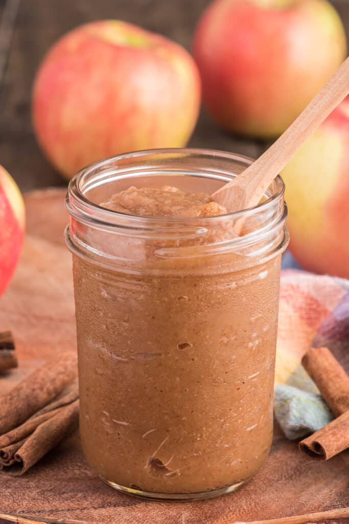 Apple butter in a glass jar with a spoon.