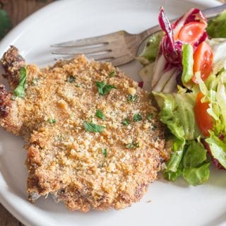 baked pork chops on a white plate with some salad