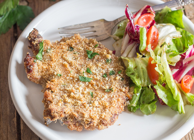 baked pork chops on a white plate with some salad