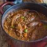 lentils and sausage stew in a red pot