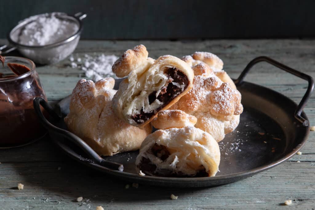 Puff pastry balls on a black tray with one cut in half.