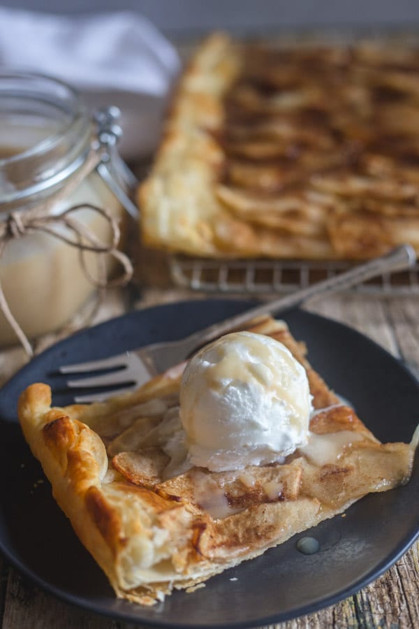 apple tart slice on a black plate and on a wire rack