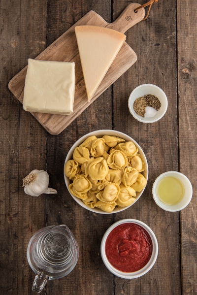 Ingredients on a wooden board for baked tortellini.