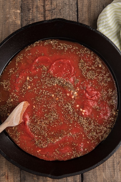 Making the sauce for the baked tortellini in a black pan.