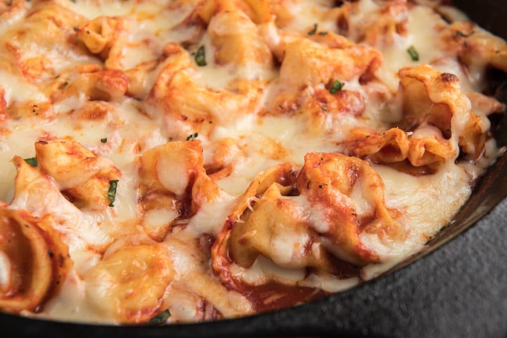 Baked tortellini in a black pan.