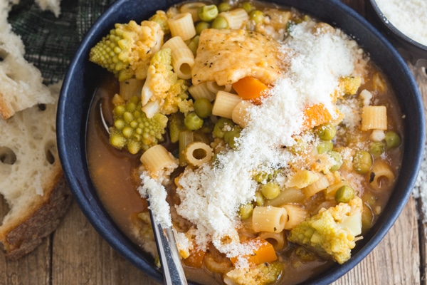 minestrone soup in a black bowl with parmesan cheese