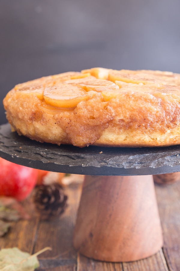 upside down apple cake on a black stand