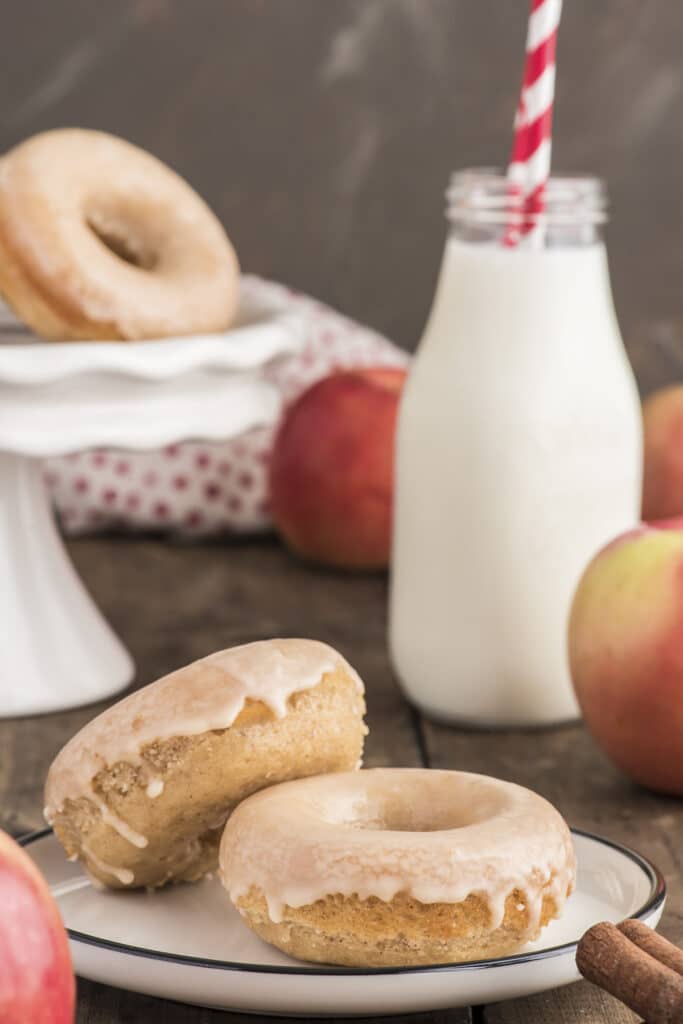 Two apple butter donuts  on a white plate with a bottle of milk.