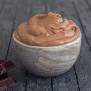 Pastry cream in a blue bowl with 3 pieces of chocolate.