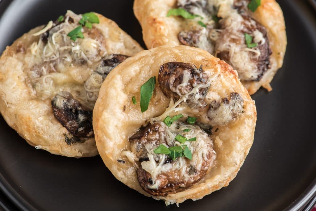 Mushroom puff pastry tarts on a black dish.