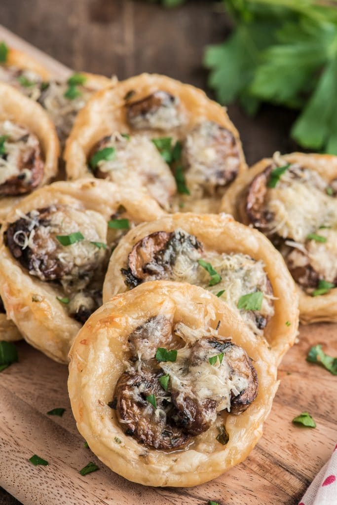 Mushroom puff pastry appetizers on a wooden board.